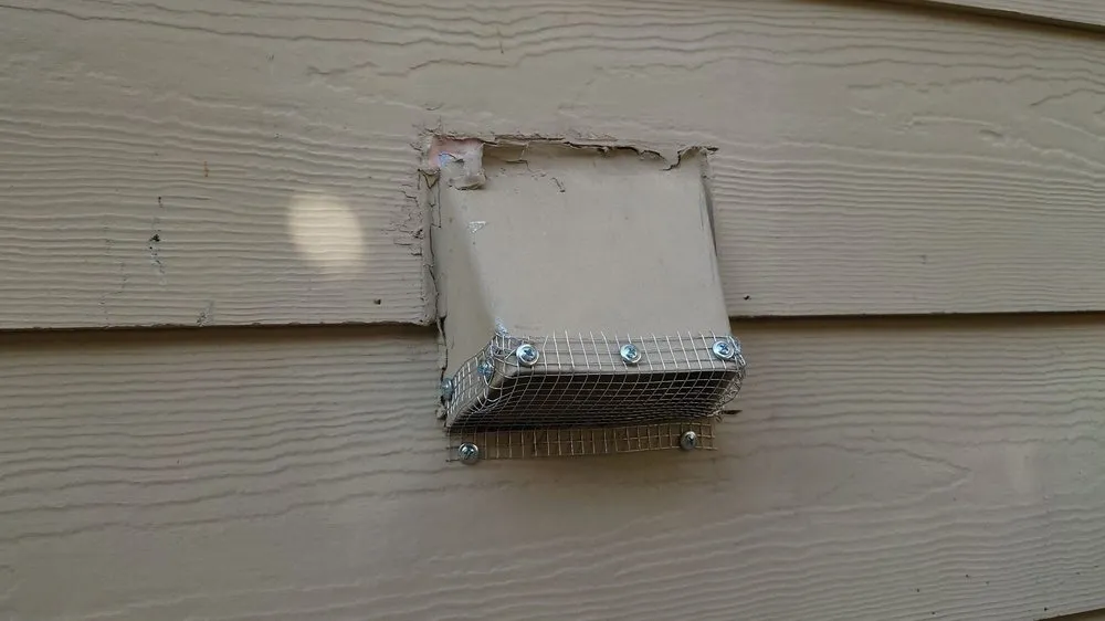 Metal mesh rodent barrier fitted over an exterior wall vent